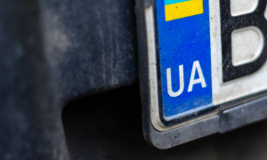 Dirty Ukrainian car license plate with UA in durable license plate frames.
